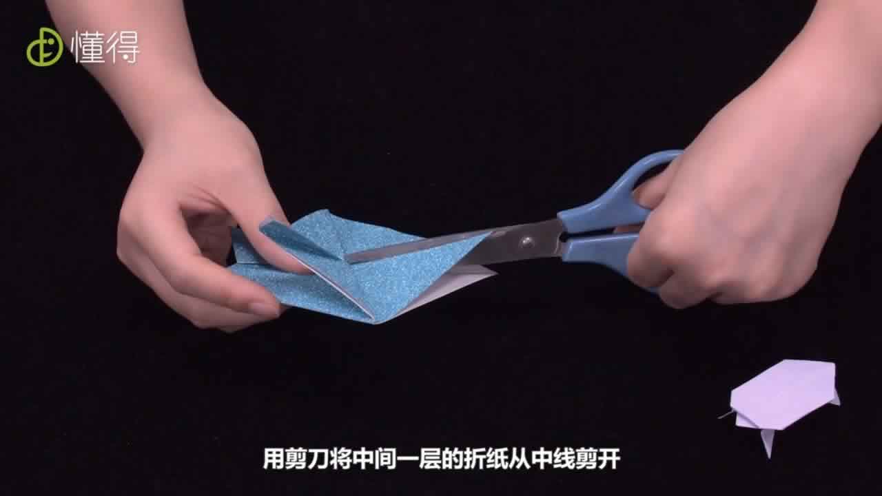 用剪刀将中间一层折纸从中线剪开